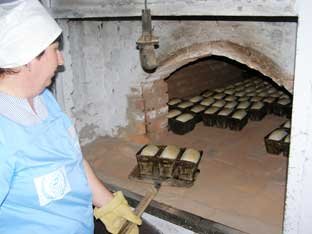 Посадка форм с хлебом в печь на сельском хлебзаводе. Хлебопекарная печь.